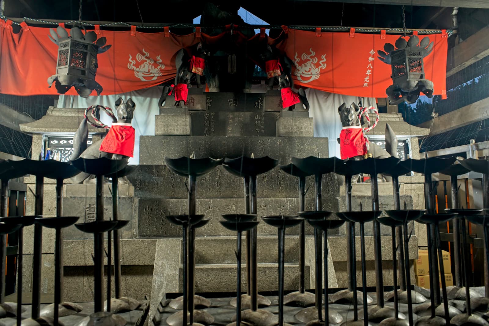 Stone fox statues and a red curtain at Fushimi Inari Taisha in Kyoto